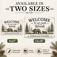 Load image into Gallery viewer, Promotional graphic showing two rustic aluminum welcome signs with bear illustrations and text options: 'Welcome to our neck of the Woods' for the Johnson Family (8x12") and 'Welcome to our neck of the Woods' for the Johnson Family (12x18"). The image includes text stating 'Available in Two Sizes,' size labels, material and origin badges, and pine branches and cones on a light background.
