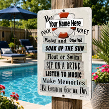 Load image into Gallery viewer, A customizable outdoor metal pool sign with a rustic white background and weathered gray lettering, featuring a red and white life preserver graphic. The sign is mounted on a wooden post next to a swimming pool with lounge chairs and a blue umbrella in the background.
