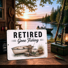 Load image into Gallery viewer, Retired Gone Fishing metal sign displayed in rustic lakeside cabin setting with fishing gear boat dock and sunset lake decor theme
