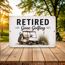 Load image into Gallery viewer, Retired Gone Golfing metal sign with vintage golf cart artwork displayed outdoors on rustic wood table at golf course clubhouse setting
