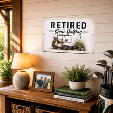 Load image into Gallery viewer, Retired Gone Golfing metal sign displayed in cozy golf-themed room with golf clubs, rustic decor, and farmhouse retirement styling
