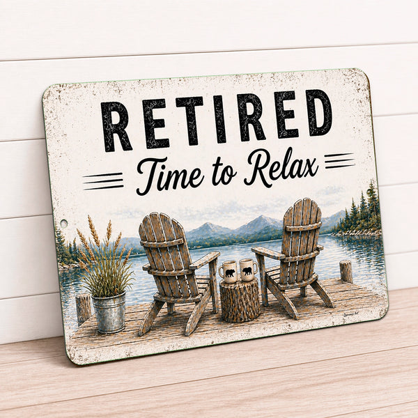 Metal sign with 'Retired Time to Relax' text and a scenic design of chairs by a lake.