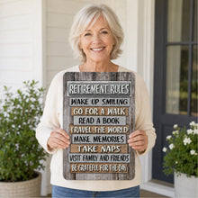 Load image into Gallery viewer, Smiling woman holding Retirement Rules metal sign on a front porch to show sign size and display style
