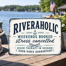 Load image into Gallery viewer, Riveraholic metal sign displayed on a waterfront dock overlooking a peaceful river with rustic outdoor decor
