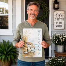 Load image into Gallery viewer, Man holding a 'Welcome' sign with a sandpiper design in front of a house.
