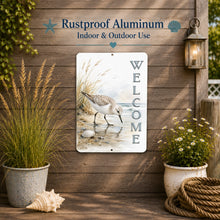 Load image into Gallery viewer, Decorative metal sign with a sandpiper design and 'Welcome' text on a wooden wall with plants and lantern.
