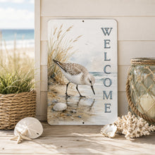 Load image into Gallery viewer, Decorative metal sign with a sandpiper bird and 'WELCOME' text, placed on a beach-themed setting with shells and a candle.
