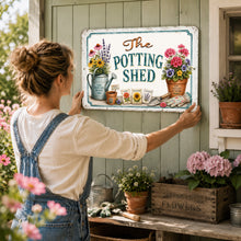 Load image into Gallery viewer, Woman hanging The Potting Shed metal sign in a charming garden shed
