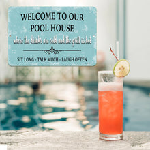 Load image into Gallery viewer, Dyenamic Art Welcome to Our Pool House Metal Sign displayed by a swimming pool with a tropical cocktail. A perfect decorative sign for outdoor bar areas and patios.
