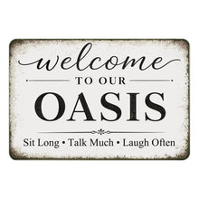 Load image into Gallery viewer, Decorative sign with text 'Welcome to our Oasis Sit Long Talk Much Laugh Often' on a white background
