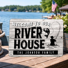 Load image into Gallery viewer, Personalized River House metal sign with custom family name, rustic fishing cabin decor displayed on a waterfront deck overlooking the river.
