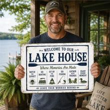 Load image into Gallery viewer, Smiling lake homeowner holding Welcome To Our Lake House metal sign at a waterfront cabin
