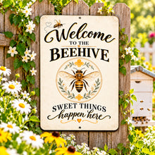 Load image into Gallery viewer, Honey bee welcome sign displayed among blooming garden flowers and fresh greenery in a bright cottage-inspired outdoor setting.
