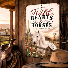 Load image into Gallery viewer, Wild Hearts &amp; Horses metal sign displayed in rustic Western horse and saddle setting
